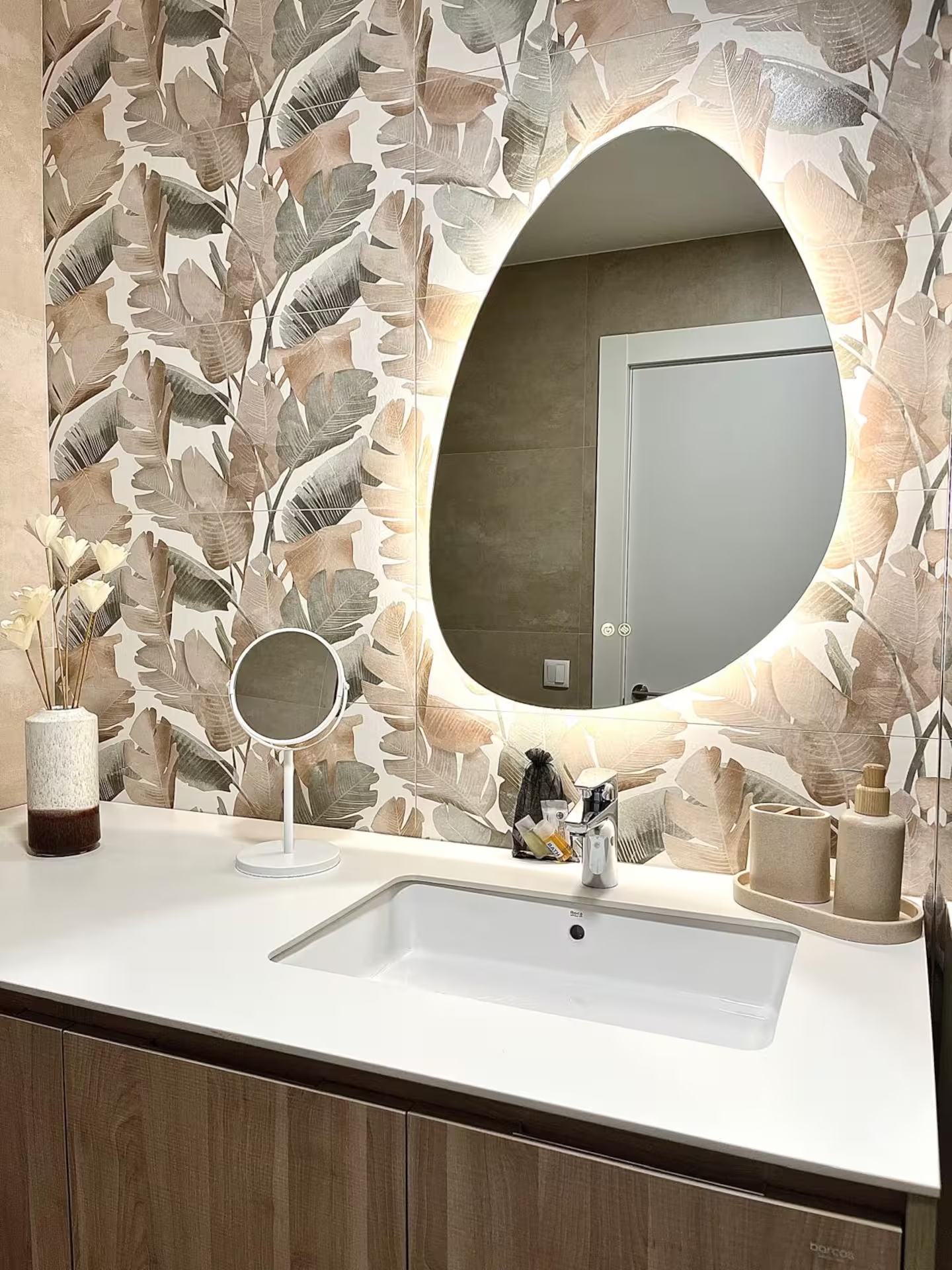 Baño moderno con papel pintado de hojas y espejo redondo